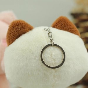 Detailed close-up of fluffy white cat plush keychain with brown ears and metal ring