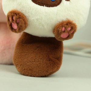 Close-up of plush toy cat with soft cream fur and detailed pink paw pads charm