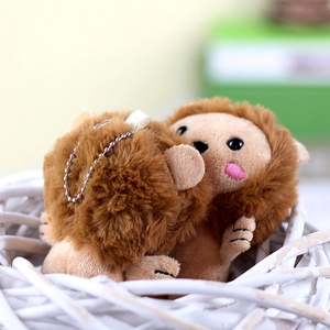 Close-up of plush lion charms with pink blush details and metal bead chains in a basket