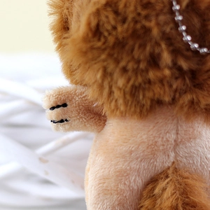 Close-up of plush lion charm featuring brown faux fur mane and silver metal chain