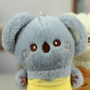 Detail eines Plüsch-Koala-Schlüsselanhängers mit grauem Fell und gelbem Outfit