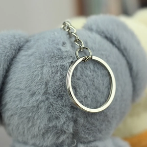 Makroaufnahme von flauschigem grauem Plüsch-Anhänger mit hochwertigem Silber-Schlüsselanhänger