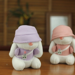 Dettaglio di coniglietti di peluche rosa e viola con cappelli e piccole borse a tracolla