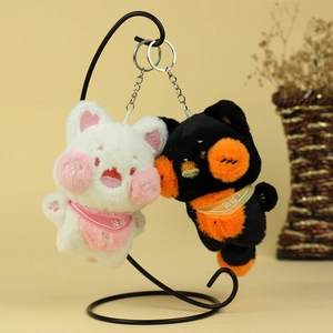 Porte-clés chats en peluche noir et blanc avec écharpes sur un support élégant