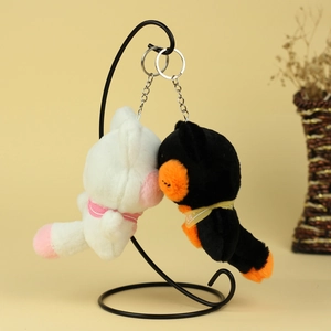 Gros plan de porte-clés chats en peluche blanc et noir suspendus sur un support