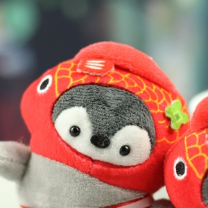 Close-up of penguin plush pendant wearing a red fish hat with detailed texture