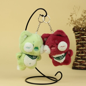 Gros plan de porte-clés chats en peluche mignons, vert et rouge, avec broderie détaillée