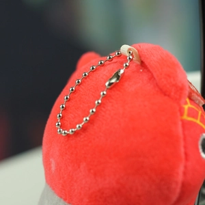 Close-up of red plush penguin keychain showing silver bead chain and soft texture