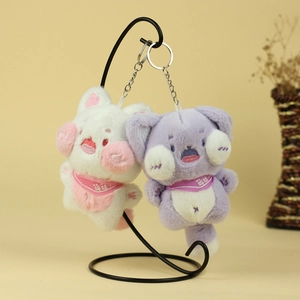 Gros plan de pendentifs chats en peluche blancs et violets avec écharpes brodées