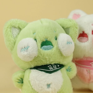 Gros plan d'un pendentif chat en peluche vert avec écharpe brodée et texture douce