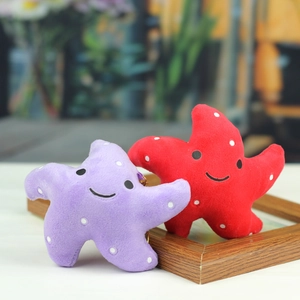Détail de porte-clés peluches étoiles de mer rouge et violette sur un cadre en bois