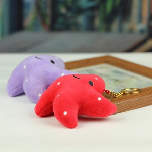 Détail de porte-clés étoile de mer en peluche rouge et violette avec visages brodés