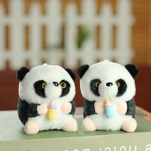 Adorable panda plush keychains with colorful milk bottles set on a green book
