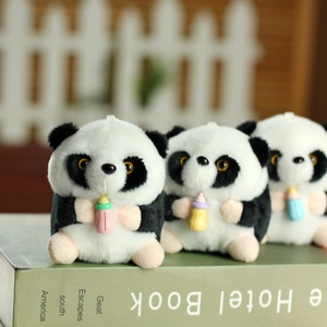 Close-up of cute panda plush keychains holding colorful milk bottles on a book