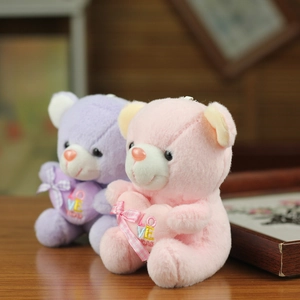 Macro view of plush bears in purple and pink holding embroidered hearts with love motif