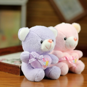 Detail of plush bears with embroidered heart and checkered bow on wooden table