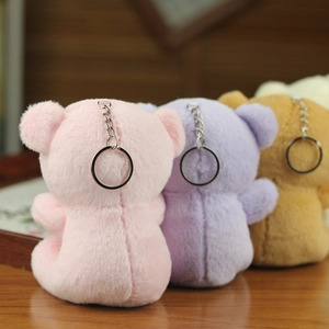 Rear view of pink, purple, and brown plush bear keychains showing stitching and metal rings