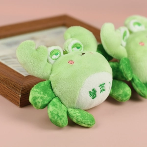 Close-up of green plush crab pendant with embroidery and cute pink blush detail