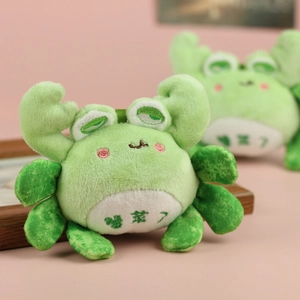 Close-up of cute plush crab-frog pendant with soft fabric and embroidered text detail