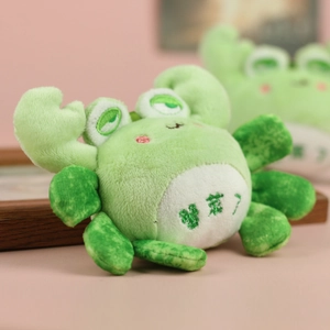 Close-up of a green plush crab keychain with cute embroidery and a soft fabric texture