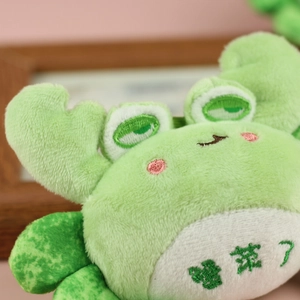 Close-up of green plush crab with intricate embroidery and soft fabric texture detail