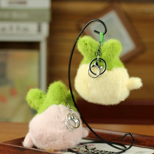 Close-up of cute plush chicken charms with green leaf ears and metal keychains