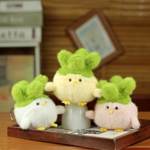 Three plush chick keychains in white, yellow, and pink with green leaf hats on a wooden tray