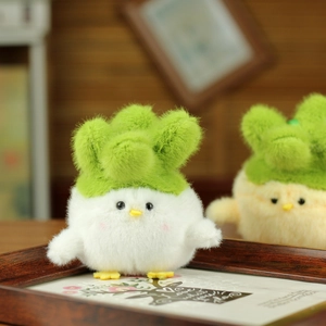 Close-up of soft white plush chicken pendant with green leaf hat on wooden tray