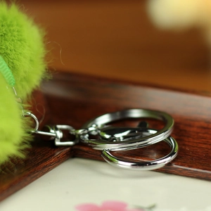 Detail of silver metal keyring with a fluffy green plush ball and rotating buckle