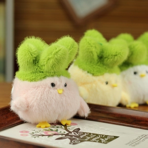 Close-up of pink plush chicken keychain with green cabbage leaf on wood background