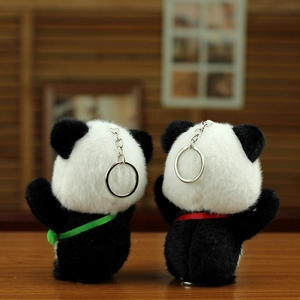 Rückansicht von zwei Panda-Plüschanhängern mit roten und grünen Bändern auf Holztisch