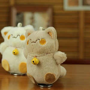Detail of cute plush cat keychains with gold bells and soft faux fur texture on wood