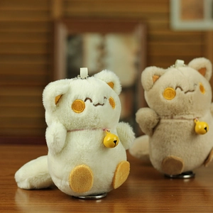 Close-up of cute plush cat keychains with pink collars and small yellow bells