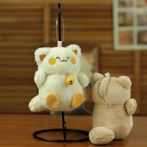 Close-up of cute plush cat keychains in beige and brown with metal chains and bells