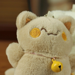 Macro detail of plush lucky cat keychain featuring soft fur texture and embroidered face