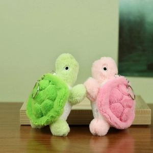 Detail of green and pink plush turtle keychains with soft texture and metal rings