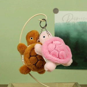Pair of cute plush turtle keychains in brown and pink hanging on a metal stand