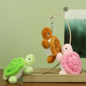 Detail of plush turtle keychains in green, pink and brown on a wooden tray