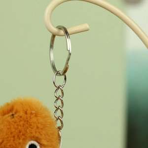 Close-up of fluffy brown plush turtle keychain with silver metal ring and link chain