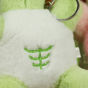 Detailed macro view of green plush turtle pendant featuring white belly with muscle embroidery