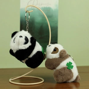Close-up of black and brown plush panda keychains with clover detail on a display stand