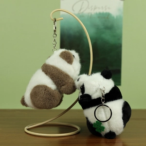 Close-up of fluffy panda plush keychains in black and brown with clover leaf detail