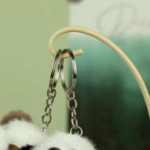 Macro shot of fluffy black and white panda plush keychain with silver metal ring and chain