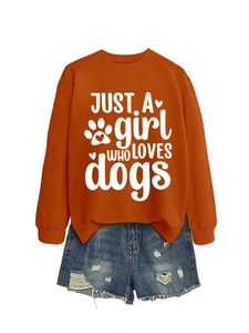 Close-up of orange sweatshirt with JUST A GIRL WHO LOVES DOGS print and ripped denim shorts