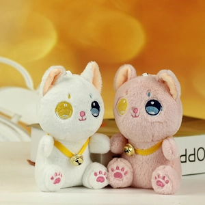 Dettaglio di ciondoli a gattino in peluche bianco e rosa con nastri e campanelli oro