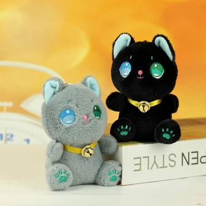 Dettaglio di portachiavi a forma di gatto in peluche con occhi ricamati e campanelli d'oro