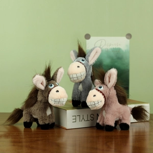 Trois adorables pendentifs âne en peluche marron, gris et rose sur un livre blanc