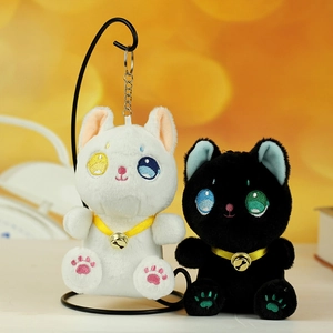 Dettaglio di portachiavi a gatto in peluche con occhi ricamati, campanelli d'oro e morbido pelo