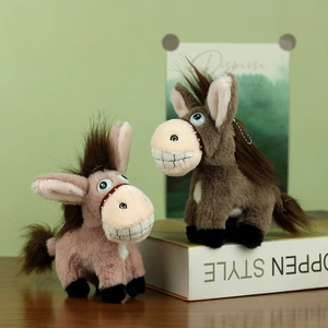 Pendentifs âne en peluche rose et marron avec grandes dents sur un bureau en bois