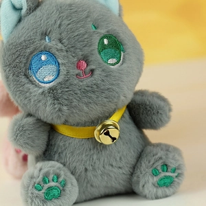 Dettaglio di ciondolo gatto di peluche grigio con pelliccia morbida e campanello d'oro